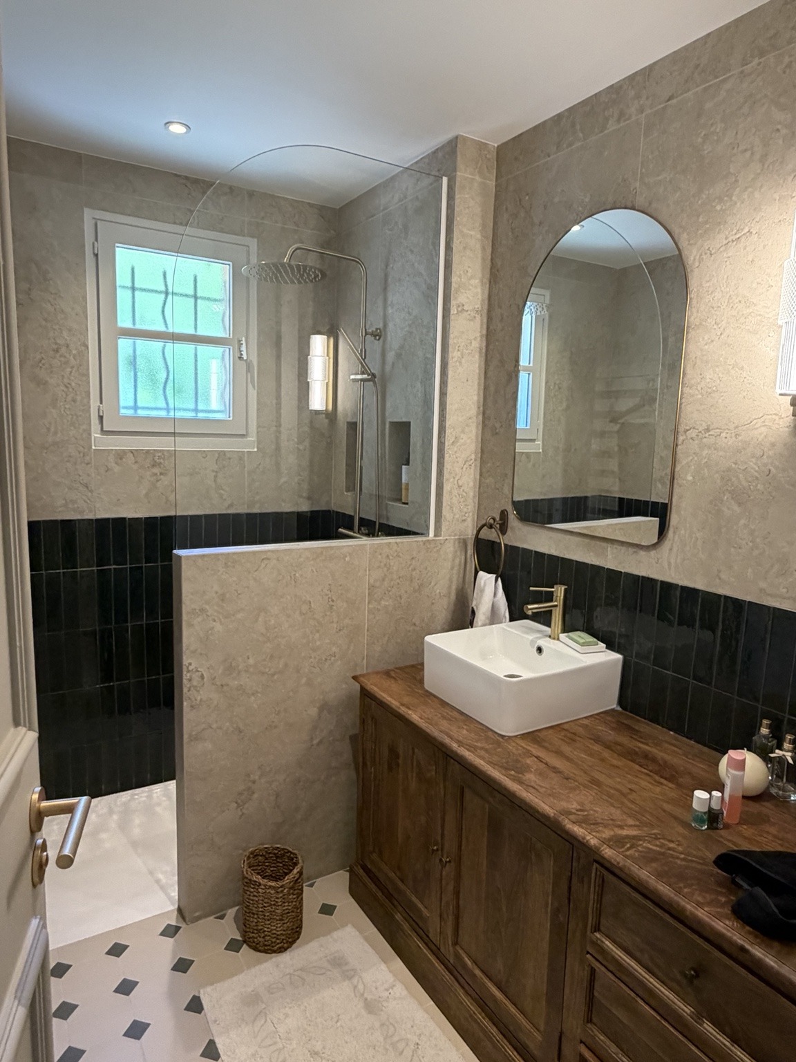 Salle de bain avec revêtement effet pierre, carrelage vert foncé, douche vitrée et meuble vasque en bois